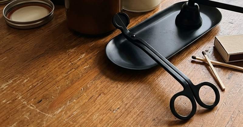 Velas encendidas con un cortamechas y un apagavelas sobre una mesa de madera